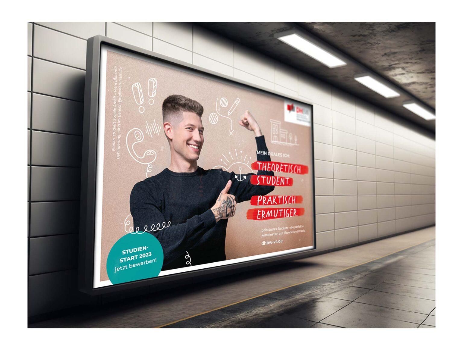 Großes Werbeplakat für die DHBW Villingen-Schwenningen, platziert unter einem Bahnhof oder einer U-Bahn-Station. Auf dem Plakat erscheint ein lächelnder junger Mann hinter dem Slogan: "Theoretisch Student. Praktisch ermutiger."