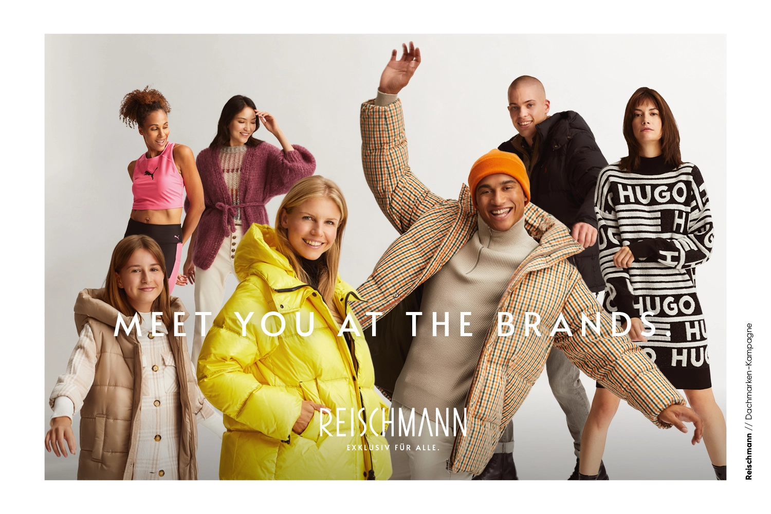 Sieben Personen in stilvollen Winteroutfits posieren fröhlich in einem Studio. Die Gruppe lächelt und nimmt verspielte Posen ein. In großer Schrift steht dort: MEET YOU AT THE BRAND. Unten ist das REISCHMANN-Logo zu sehen.